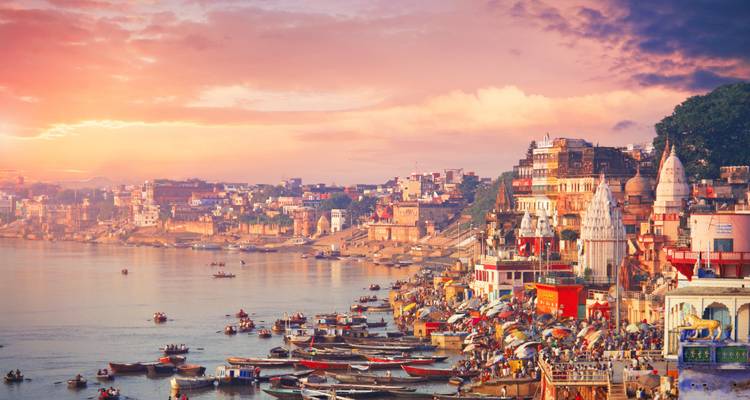 Vista panorámica de los ghats de Varanasi a lo largo del río con edificios coloridos y botes.