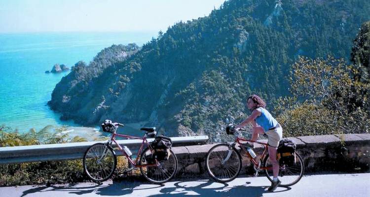 Deux cyclistes sur une route surplombant une falaise côtière et la mer.