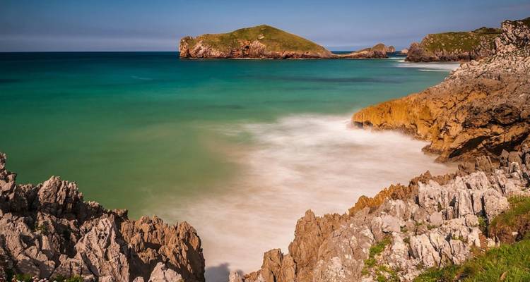 Zone côtière rocheuse avec eau turquoise et petites îles.