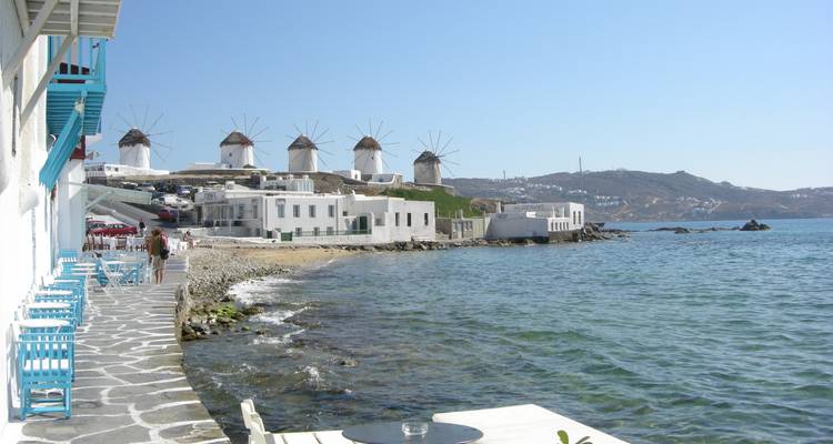 Vue côtière de moulins à vent traditionnels sur l'île de Mykonos avec un ciel dégagé.