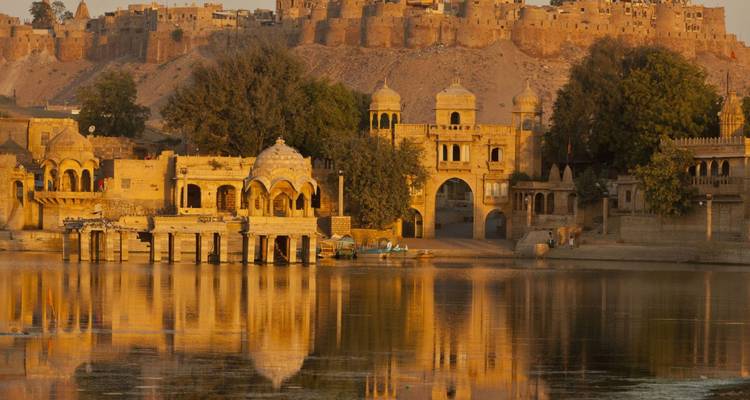 Arquitectura histórica en Jaisalmer con reflejo del atardecer en el lago.