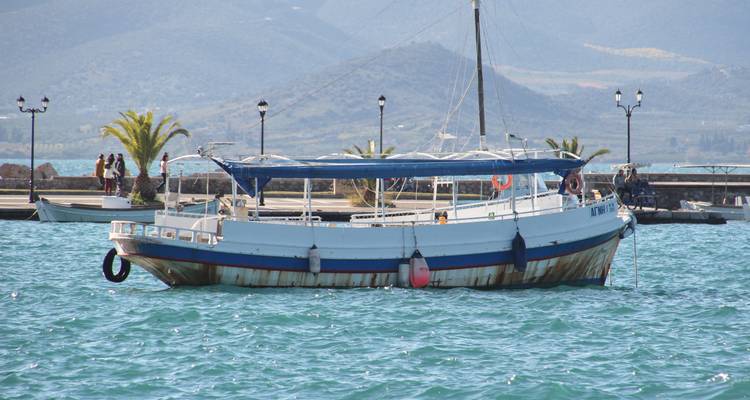 Pequeño bote amarrado en aguas tranquilas con montañas distantes.