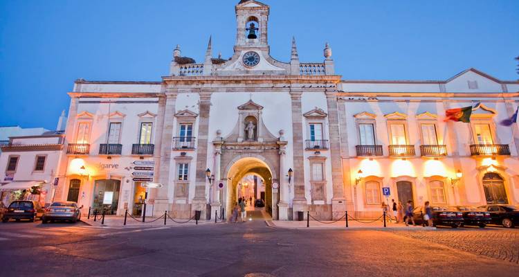 Un bâtiment historique illuminé au crépuscule avec des voitures garées devant