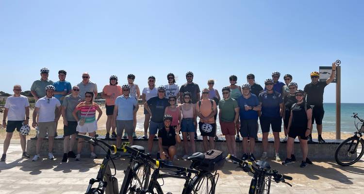 Un grand groupe de cyclistes posant sur une promenade en bord de mer
