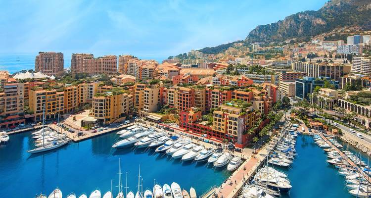 Vue aérienne du port de Monaco avec des yachts et des bâtiments colorés.