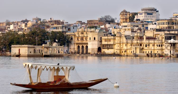 Blick auf die Stadt Udaipur von einem See aus mit historischen Gebäuden.