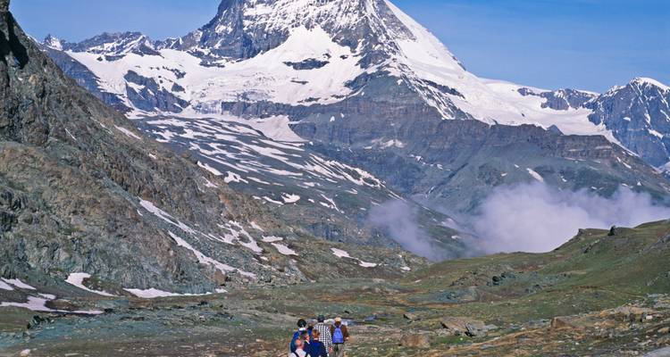 Una familia haciendo senderismo en las montañas con el Matterhorn a lo lejos.