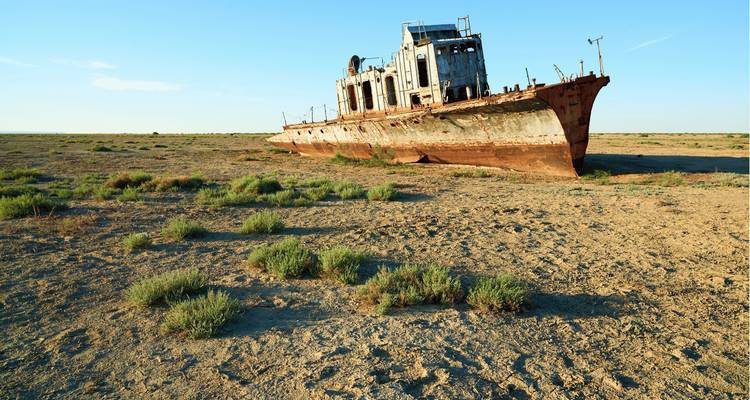 Navire rouillé abandonné sur une plaine désertique et aride.