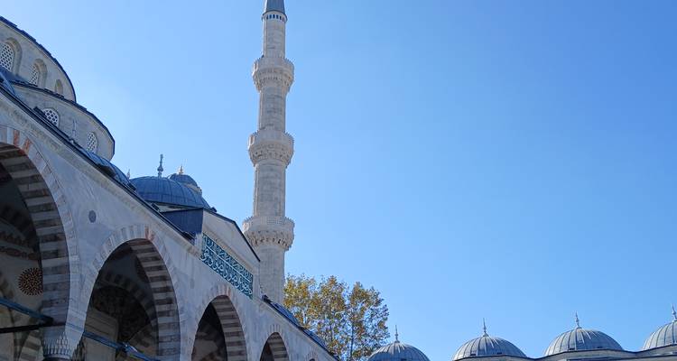 Una mezquita con un minarete alto bajo un cielo azul despejado.