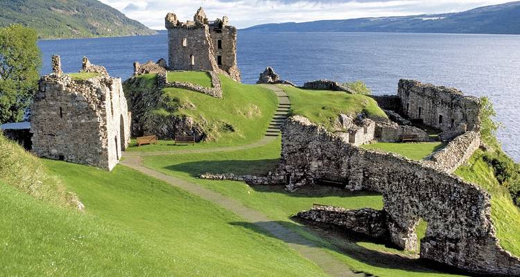 Ruinen von Urquhart Castle, die neben den tiefblauen Gewässern von Loch Ness unter klarem Himmel thronen