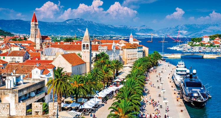 Promenade colorée du front de mer de Trogir bordée de palmiers, de cafés et de yachts amarrés