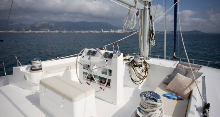 Poste de barre sur le pont supérieur d'un catamaran à voile avec l'horizon côtier au loin