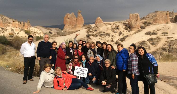 Un groupe de touristes posant avec des formations rocheuses uniques en arrière-plan.