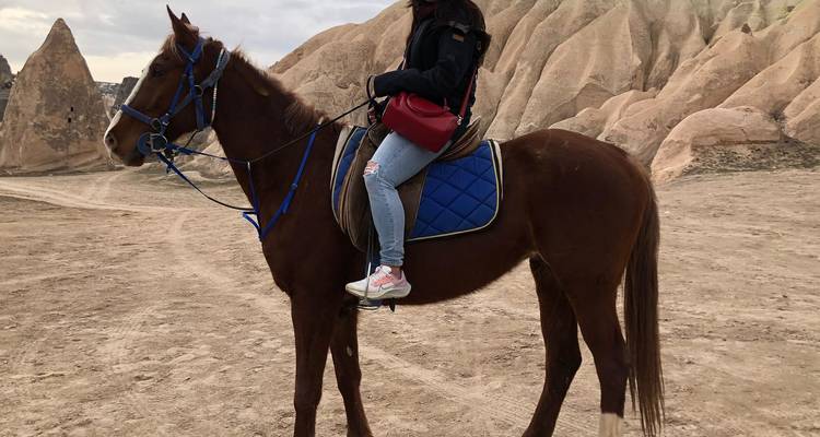 Personne montant à cheval dans un paysage désertique.