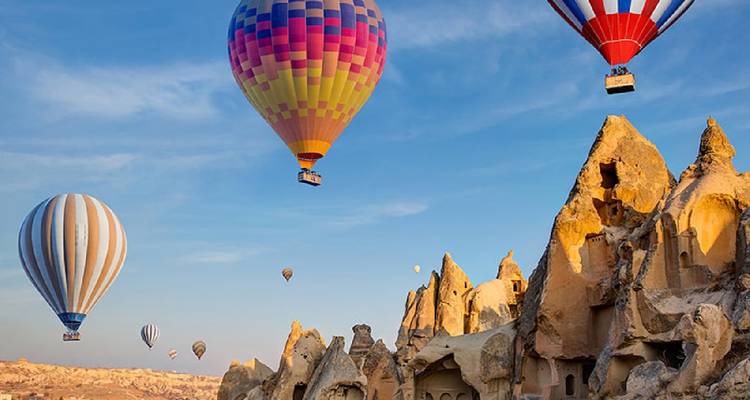 Montgolfières volant au-dessus de formations rocheuses au lever du soleil.