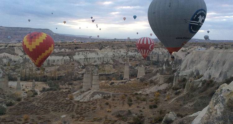 Montgolfières dans un paysage désertique avec des formations rocheuses.