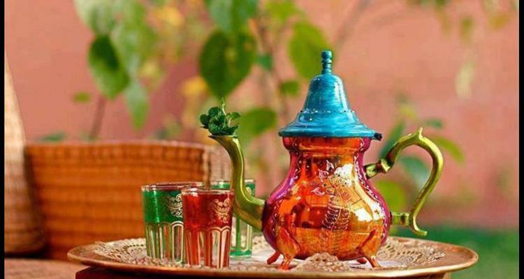 Théière colorée avec des verres sur un plateau traditionnel.