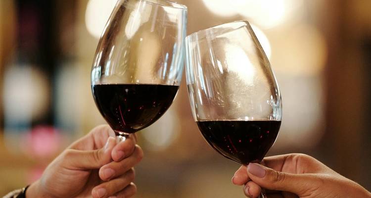 Dos copas de vino tinto chocando en un brindis de celebración