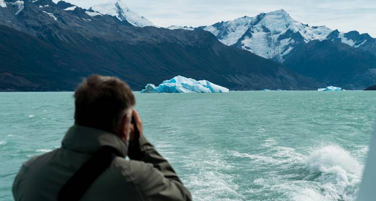 Une personne observant des icebergs depuis un bateau dans un lac glaciaire.