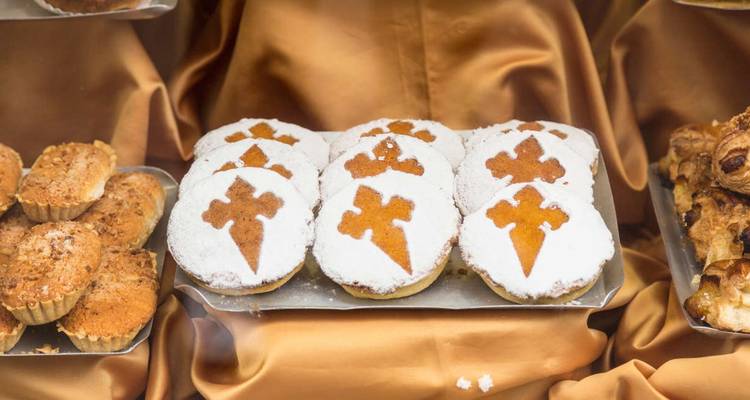 Primer plano de pasteles tradicionales con un diseño de cruz sobre un fondo dorado.