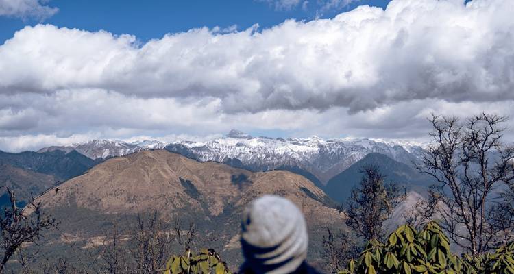 Excursionista contemplando una cordillera panorámica con picos cubiertos de nieve.