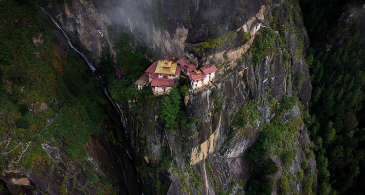 Taktsang Monastery perched on a cliff surrounded by lush greenery.