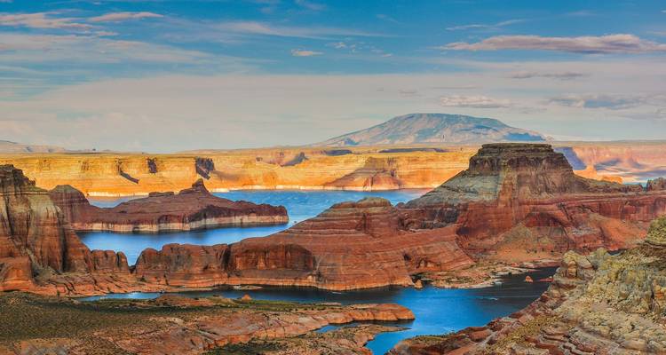 Vue à couper le souffle du lac Powell avec des formations rocheuses rouges et un arrière-plan montagneux.
