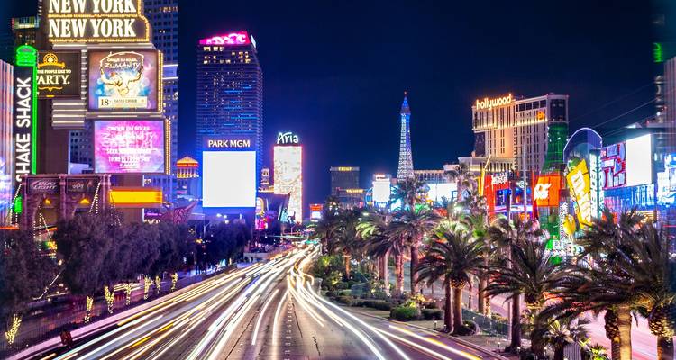 Vue nocturne vibrante du Strip de Las Vegas avec des enseignes illuminées et le mouvement flou des feux de circulation.