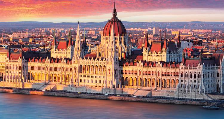 La lumière dorée du coucher de soleil baigne l'ornementé Parlement hongrois le long du Danube à Budapest.