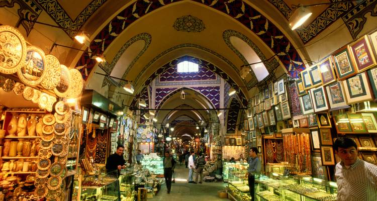 Intérieur animé du Grand Bazar d'Istanbul avec des plafonds voûtés ornés, des vitrines lumineuses et des clients qui flânent.