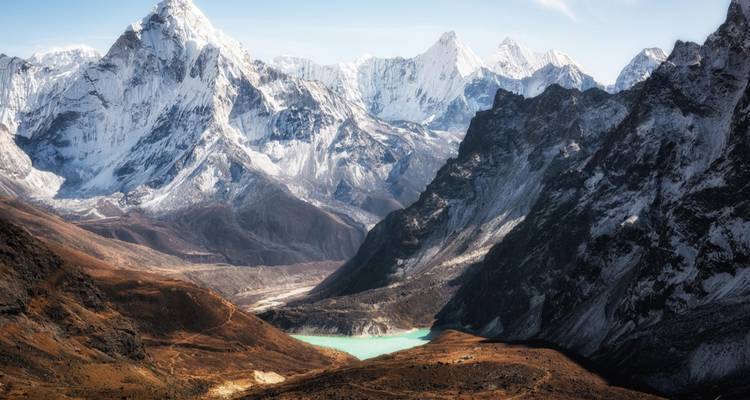 Paisaje montañoso dramático con un glaciar y un lago turquesa.