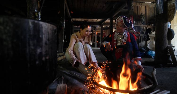 Moment culturel avec deux individus près d'un feu dans un cadre rustique.