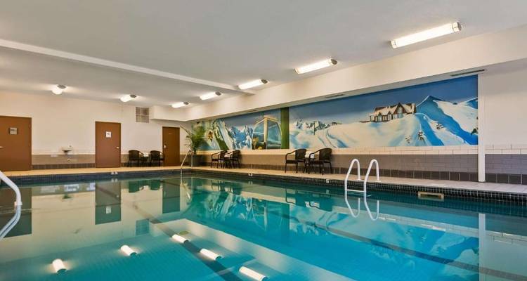 Área de piscina cubierta con sillas y un mural de montaña en la pared.