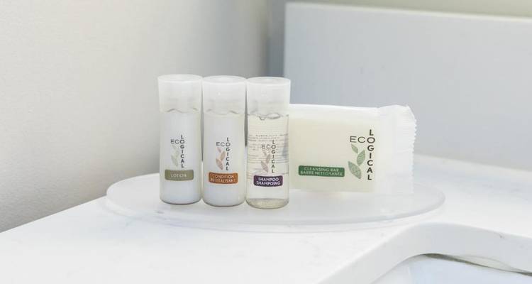 Primer plano de las comodidades de la habitación de hotel incluyendo pequeñas botellas de loción y champú.