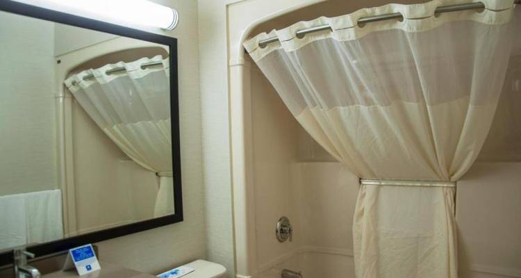 Espejo de baño reflejando un área de bañera moderna y limpia.