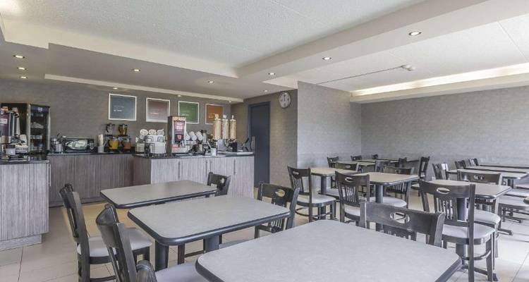 Área de comedor vacía del hotel con mesas y estación de café.