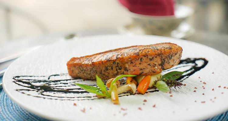 Gourmet-Gericht mit Lachs und Gemüse serviert auf einem eleganten Teller.