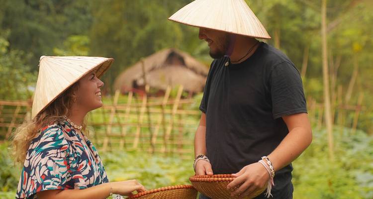 Zwei Menschen, die sich in einem Feld unterhalten und traditionelle kegelförmige Hüte tragen.