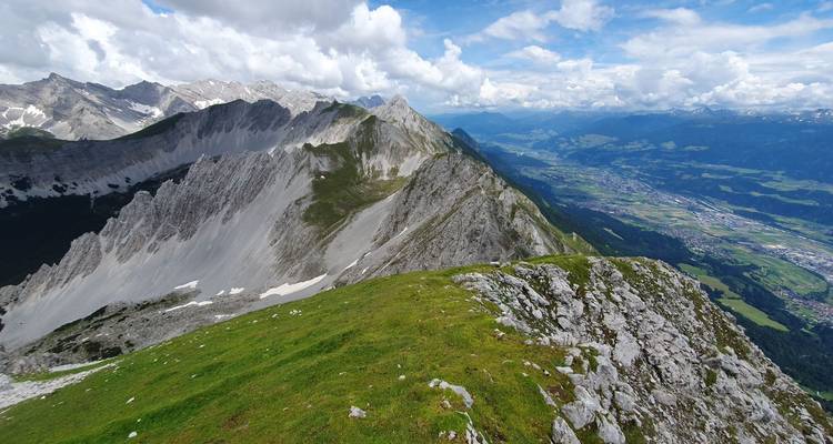 Vaste chaîne de montagnes avec nuages et vallées.