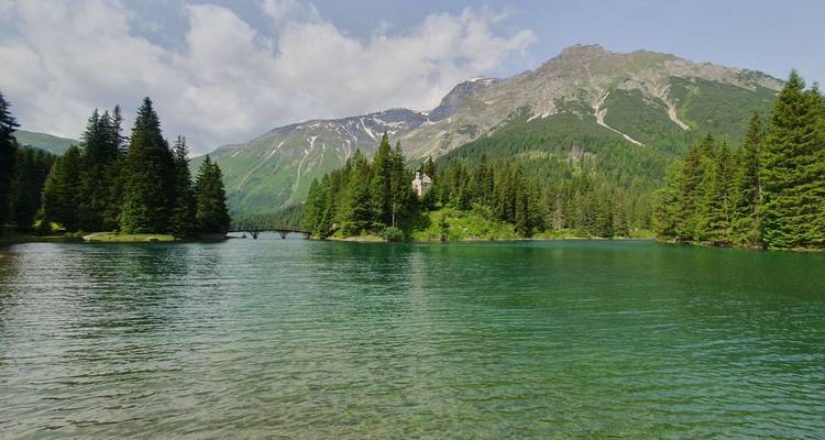 Un lac serein avec une forêt et des montagnes en arrière-plan.