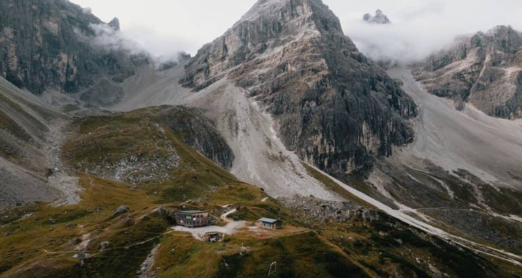 Une cabane isolée sur fond de montagne avec des nuages.