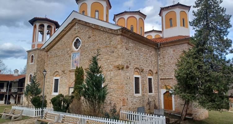 Église en pierre avec des dômes et des arbres environnants.