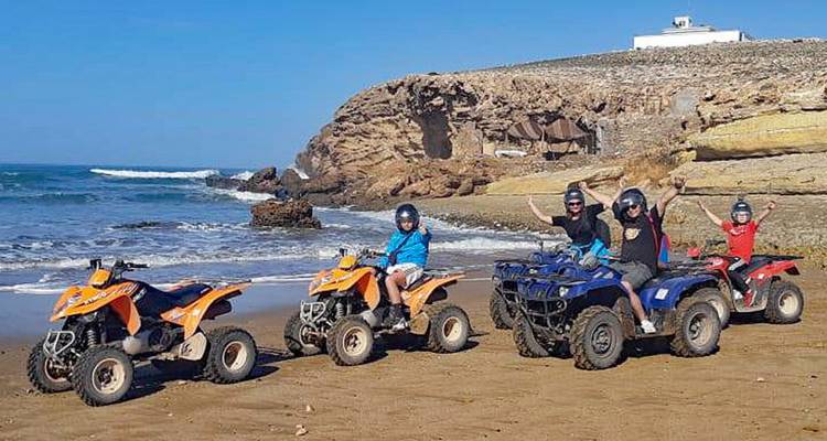 Gruppe auf Quads an einem felsigen Strand.