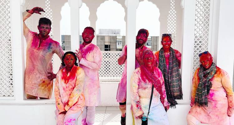 Gruppe von Menschen mit buntem Pulver auf ihrer Kleidung, die Holi feiern.