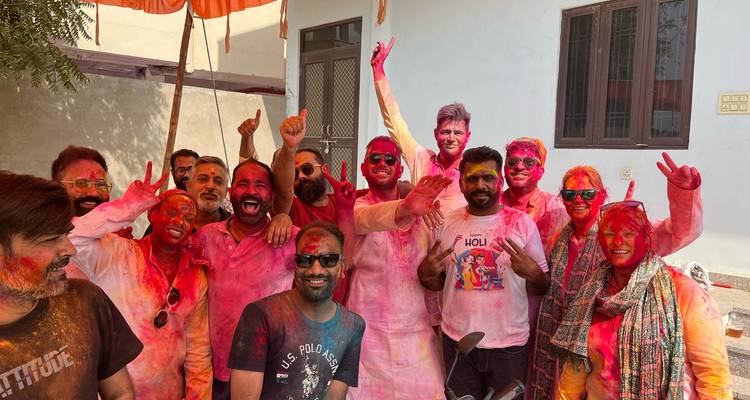Große Gruppe von Menschen, die während des Holi-Festivals mit buntem Pulver bedeckt sind.