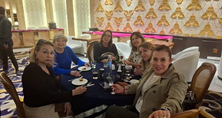 Eine Gruppe von Frauen, die um einen Tisch in einem Restaurant sitzen und sich unterhalten.