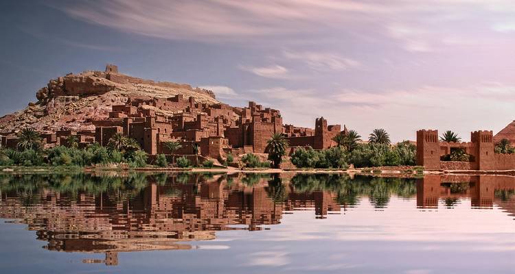 Un ancien village fortifié marocain se reflétant dans une étendue d'eau calme.