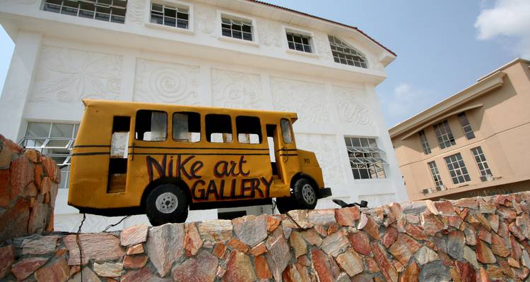 Un modèle décoratif d'un bus devant un bâtiment blanc étiqueté 'Nike Art Gallery'.