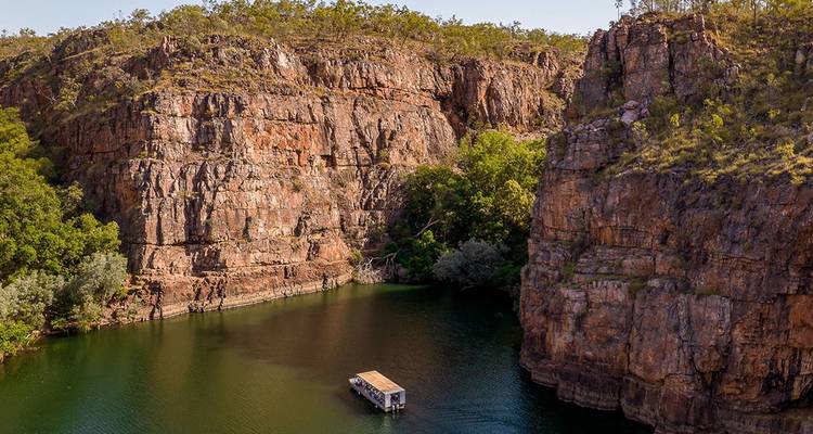 Bateau flottant dans une rivière entre des falaises rocheuses escarpées