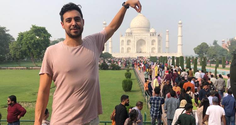 Een persoon die poseert met de Taj Mahal op de achtergrond.